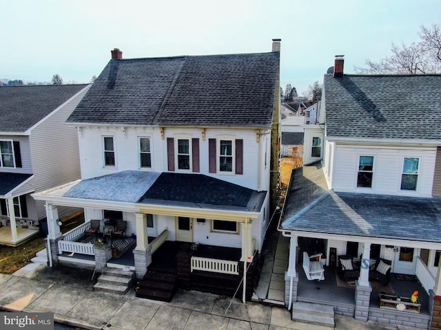 view of front of property with a porch, roof with shingles, and a chimney