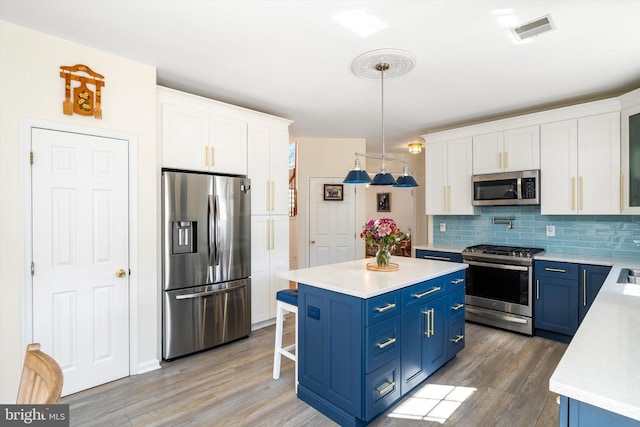 kitchen featuring blue cabinetry, white cabinets, visible vents, and appliances with stainless steel finishes