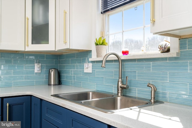 kitchen featuring light countertops, white cabinets, blue cabinetry, and a sink