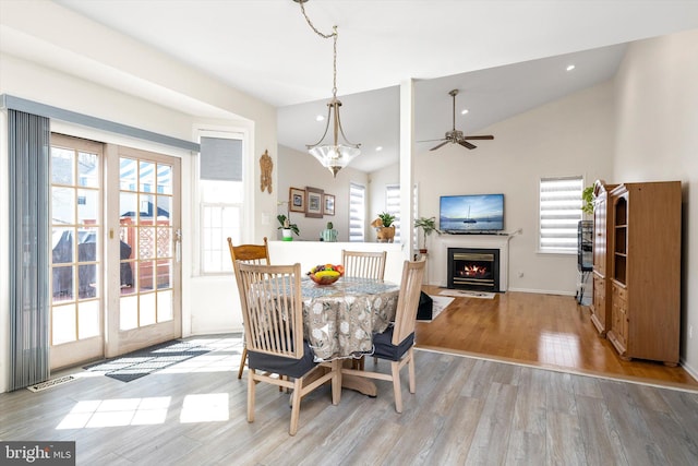 dining space featuring a fireplace with flush hearth, wood finished floors, and a wealth of natural light