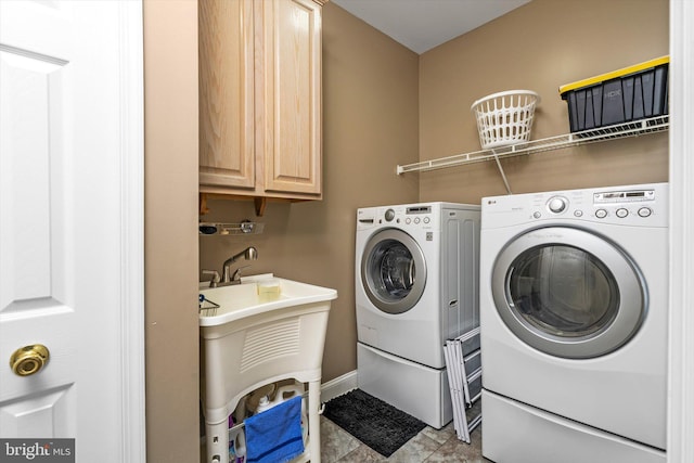 washroom featuring cabinet space, washing machine and dryer, baseboards, and a sink