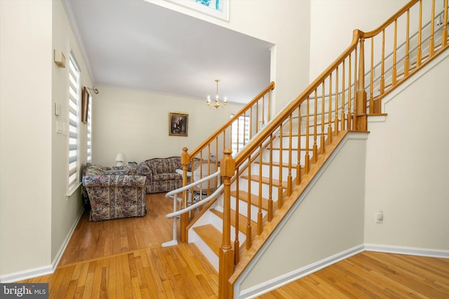 staircase with baseboards, wood-type flooring, and a chandelier