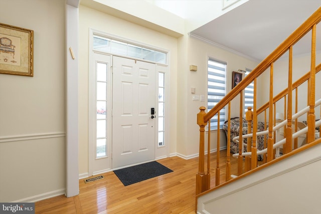 entrance foyer with visible vents, plenty of natural light, light wood-style floors, and stairs