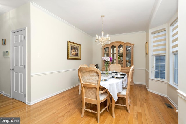 dining room with visible vents, crown molding, baseboards, a chandelier, and light wood-style floors