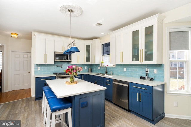 kitchen with visible vents, blue cabinetry, light countertops, stainless steel appliances, and a sink