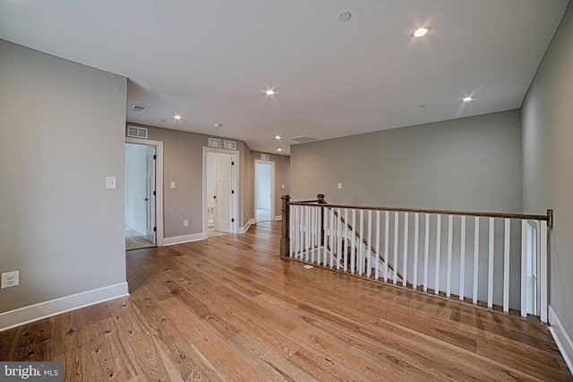 unfurnished room featuring recessed lighting, wood finished floors, visible vents, and baseboards