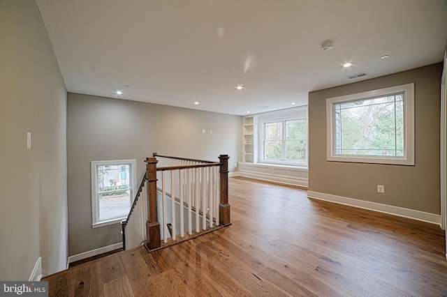 interior space with a healthy amount of sunlight, visible vents, wood finished floors, and an upstairs landing