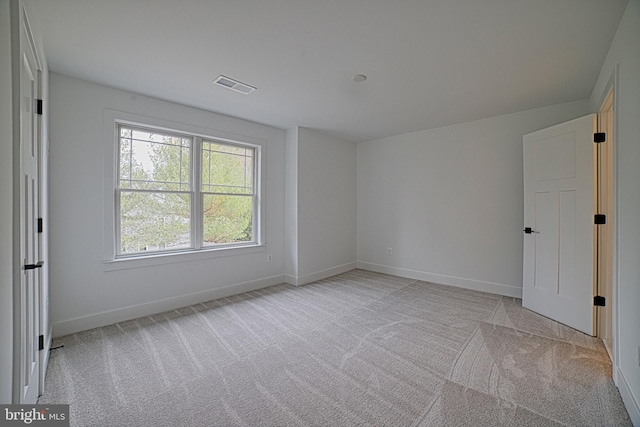 unfurnished room with baseboards, visible vents, and light colored carpet