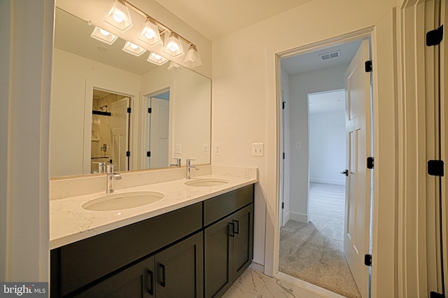 bathroom featuring marble finish floor, double vanity, a sink, and baseboards