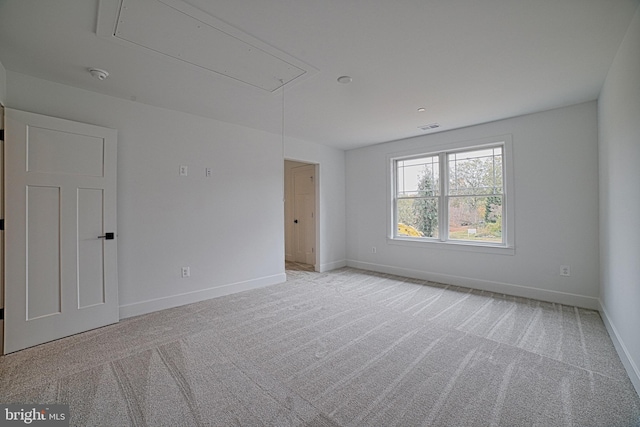 empty room featuring visible vents, baseboards, attic access, and light colored carpet