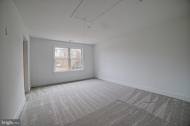 spare room featuring visible vents, carpet, attic access, and baseboards