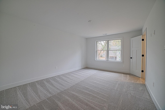 spare room featuring light carpet, visible vents, and baseboards