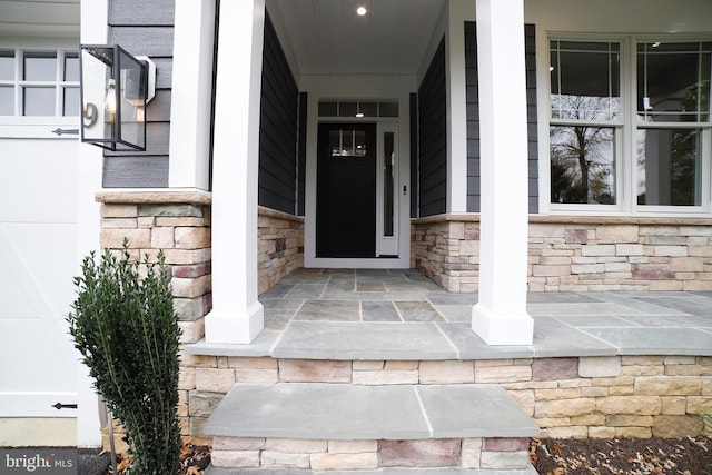 doorway to property with stone siding and a porch