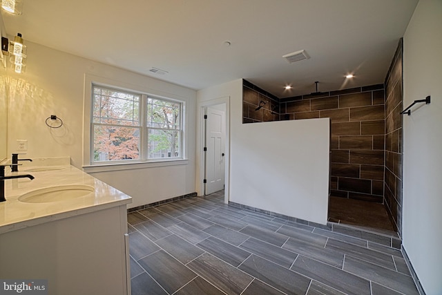 bathroom with double vanity, visible vents, a sink, and a walk in shower