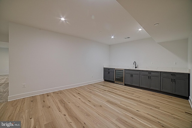 bar featuring baseboards, wine cooler, light wood-style floors, a sink, and recessed lighting