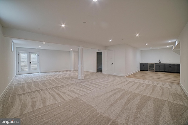 basement featuring baseboards, light colored carpet, french doors, a sink, and recessed lighting