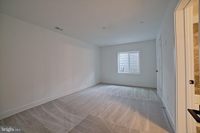 empty room with baseboards, visible vents, and light colored carpet