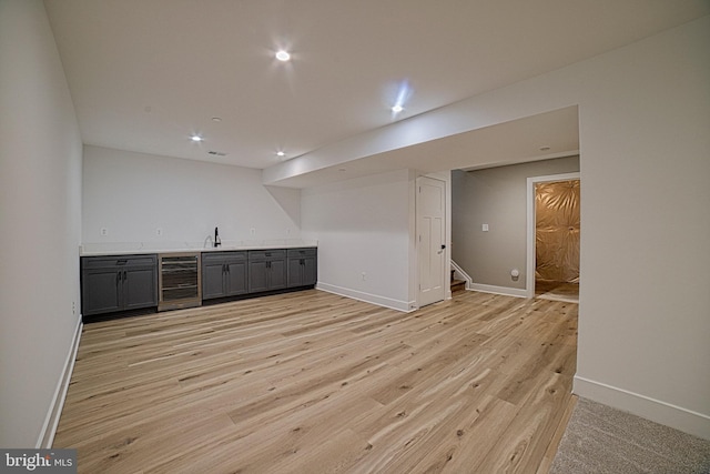 bar with light wood-type flooring, stairs, wine cooler, and indoor wet bar