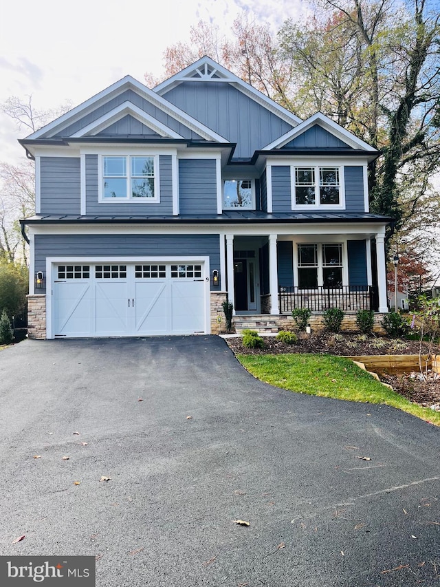 craftsman-style house featuring aphalt driveway, a porch, an attached garage, board and batten siding, and stone siding