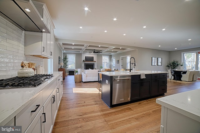 kitchen with a large fireplace, open floor plan, stainless steel appliances, a sink, and exhaust hood