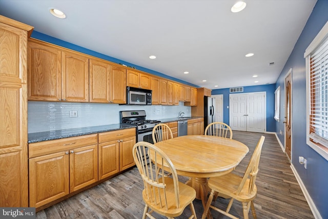 kitchen featuring appliances with stainless steel finishes, dark wood-style flooring, visible vents, and decorative backsplash