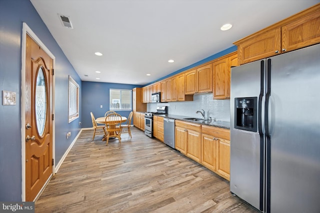 kitchen featuring light wood-style flooring, a sink, visible vents, appliances with stainless steel finishes, and backsplash