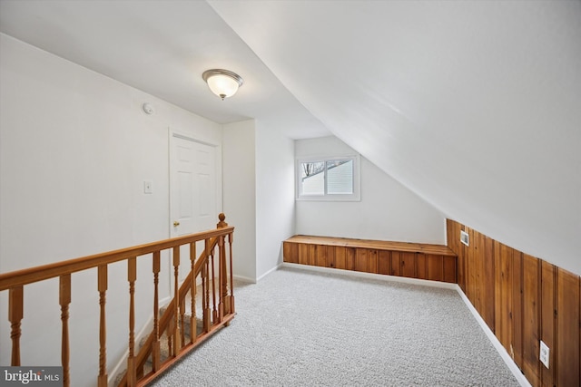 bonus room featuring lofted ceiling, wood walls, and carpet flooring