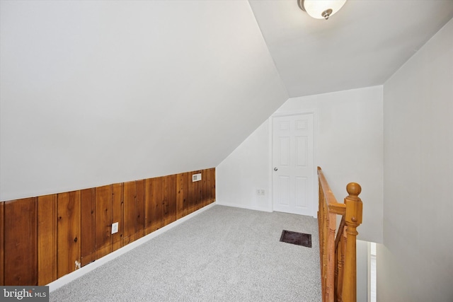 additional living space with lofted ceiling, carpet, visible vents, and wooden walls