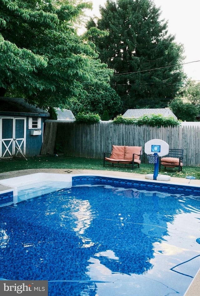 view of pool featuring an outbuilding, a storage unit, fence, and a fenced in pool