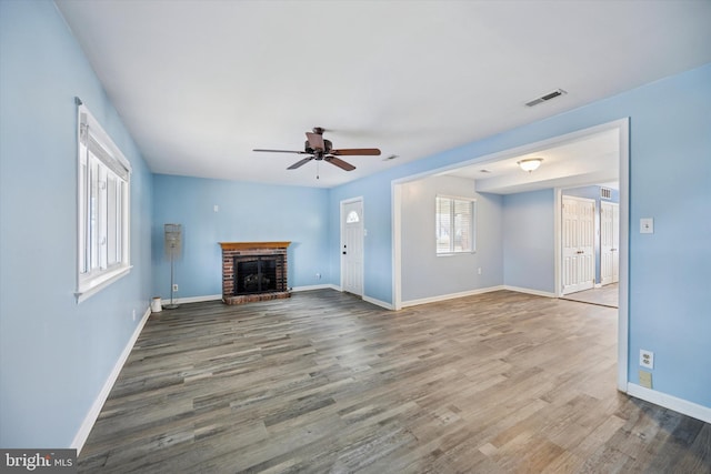 unfurnished living room featuring baseboards, a fireplace, visible vents, and wood finished floors