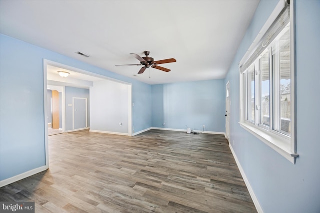 empty room featuring visible vents, ceiling fan, baseboards, and wood finished floors