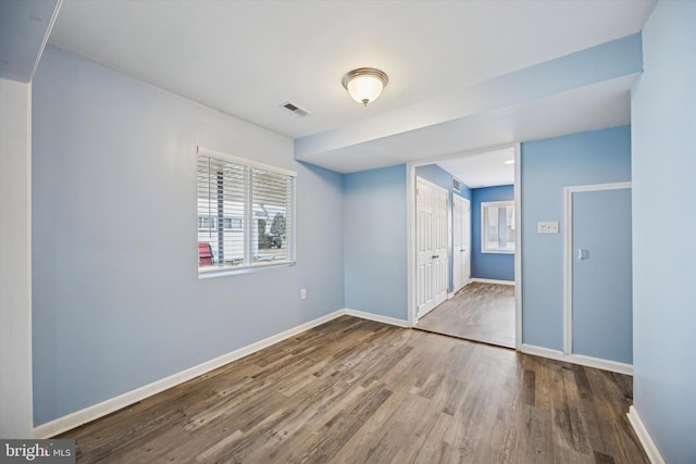 empty room with visible vents, baseboards, and wood finished floors