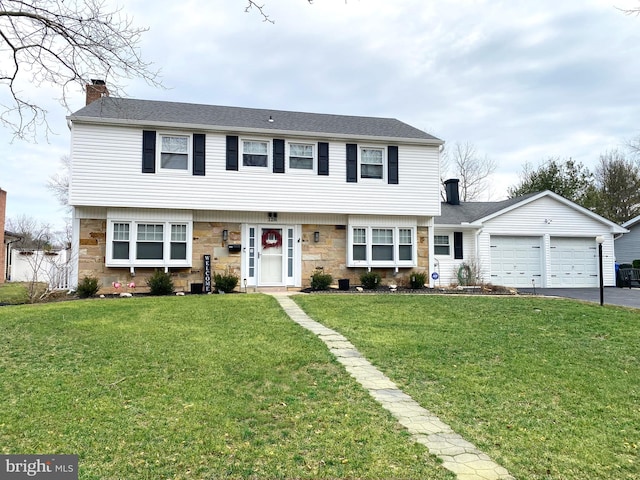 colonial-style house with driveway, stone siding, a chimney, and a front yard