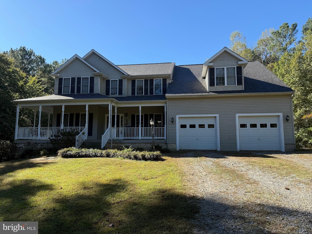 view of front of home featuring covered porch, driveway, a front yard, and a garage