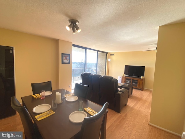 dining area with a wall of windows, ceiling fan, a textured ceiling, and light wood finished floors