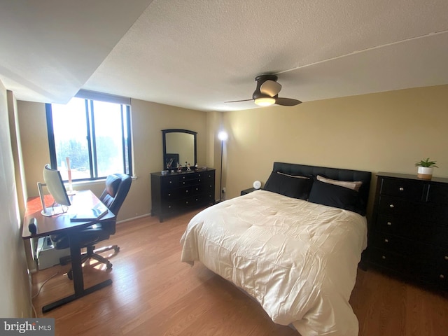 bedroom with light wood-style floors, ceiling fan, and a textured ceiling