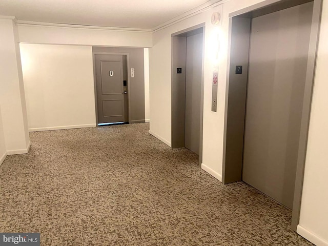 corridor featuring elevator, carpet, ornamental molding, and baseboards