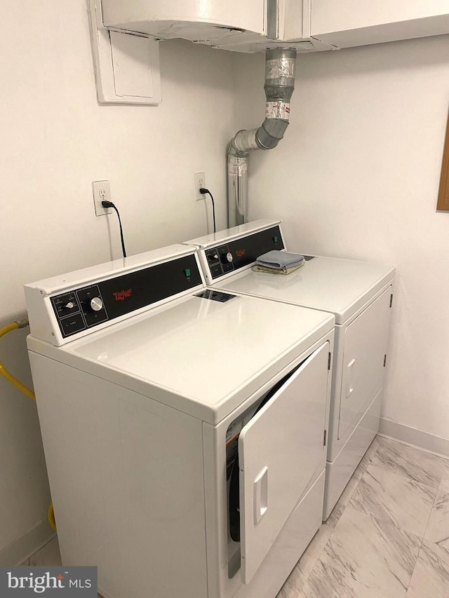 clothes washing area featuring marble finish floor, washing machine and dryer, laundry area, and baseboards