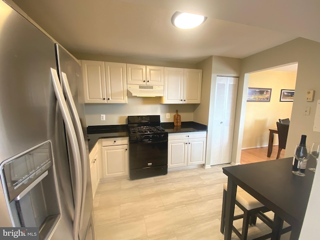 kitchen with black gas range oven, under cabinet range hood, white cabinets, and stainless steel fridge with ice dispenser