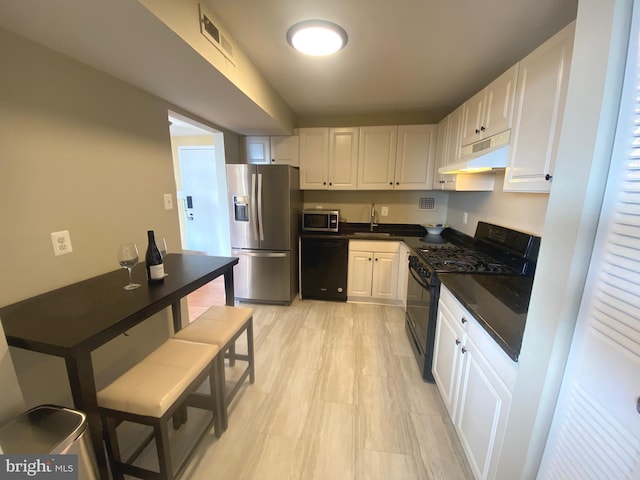 kitchen with white cabinetry, a sink, under cabinet range hood, and black appliances