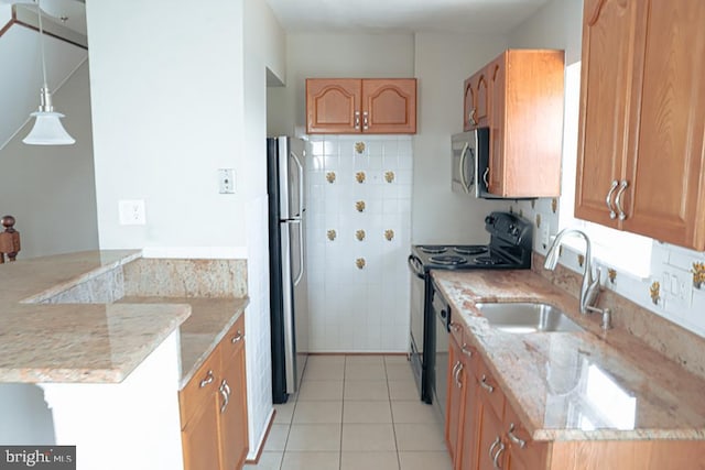 kitchen with light stone countertops, light tile patterned floors, appliances with stainless steel finishes, a peninsula, and a sink