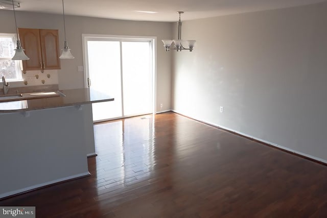 unfurnished dining area featuring dark wood finished floors and a chandelier