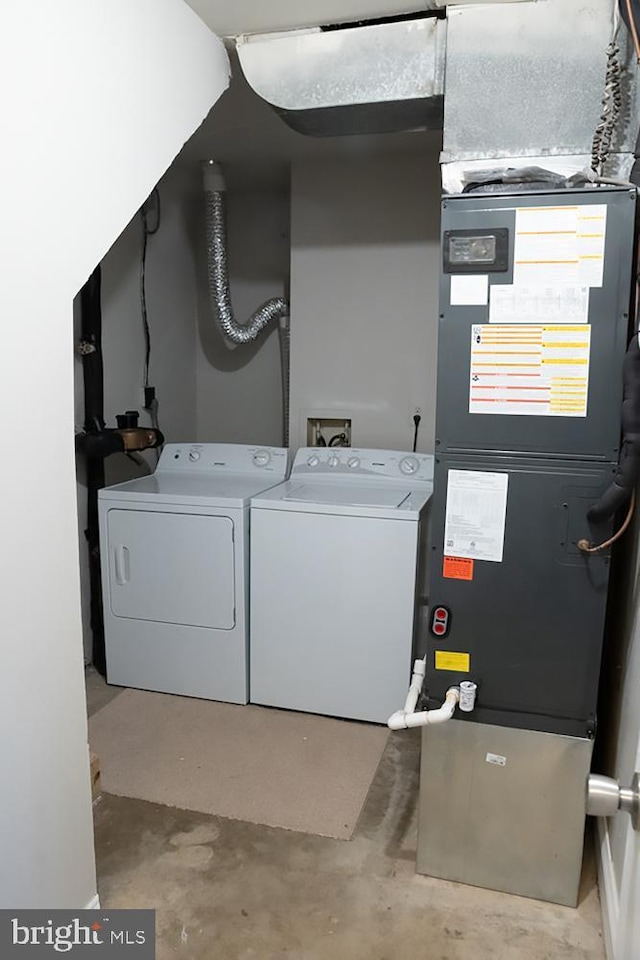 clothes washing area featuring heating unit, laundry area, and washer and dryer