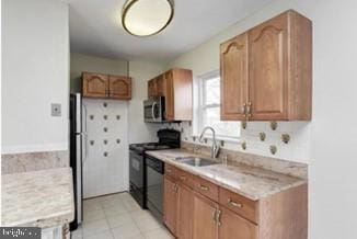 kitchen featuring dishwashing machine, freestanding refrigerator, a sink, stove, and stainless steel microwave