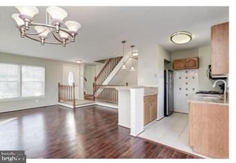 kitchen with light wood finished floors, light countertops, an inviting chandelier, brown cabinetry, and a sink