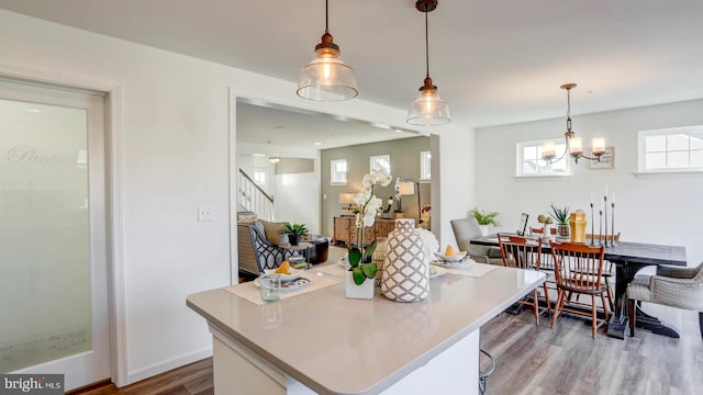 kitchen with a center island, decorative light fixtures, light countertops, wood finished floors, and a chandelier