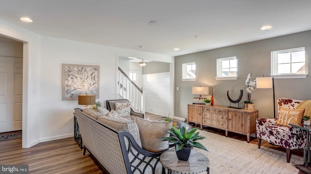 living room featuring recessed lighting, wood finished floors, baseboards, and stairs