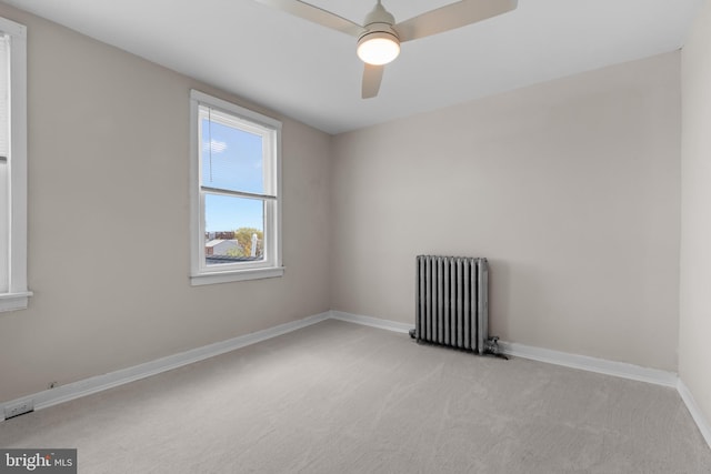 unfurnished room with a ceiling fan, baseboards, light carpet, and radiator heating unit
