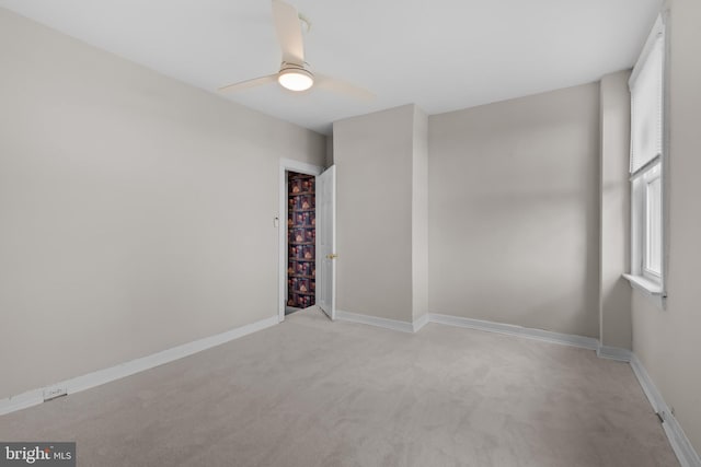 spare room featuring a ceiling fan, baseboards, and light colored carpet