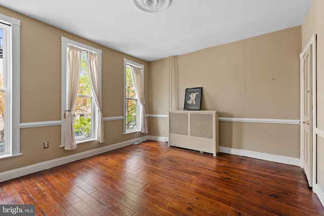 empty room with wood-type flooring, radiator, and baseboards